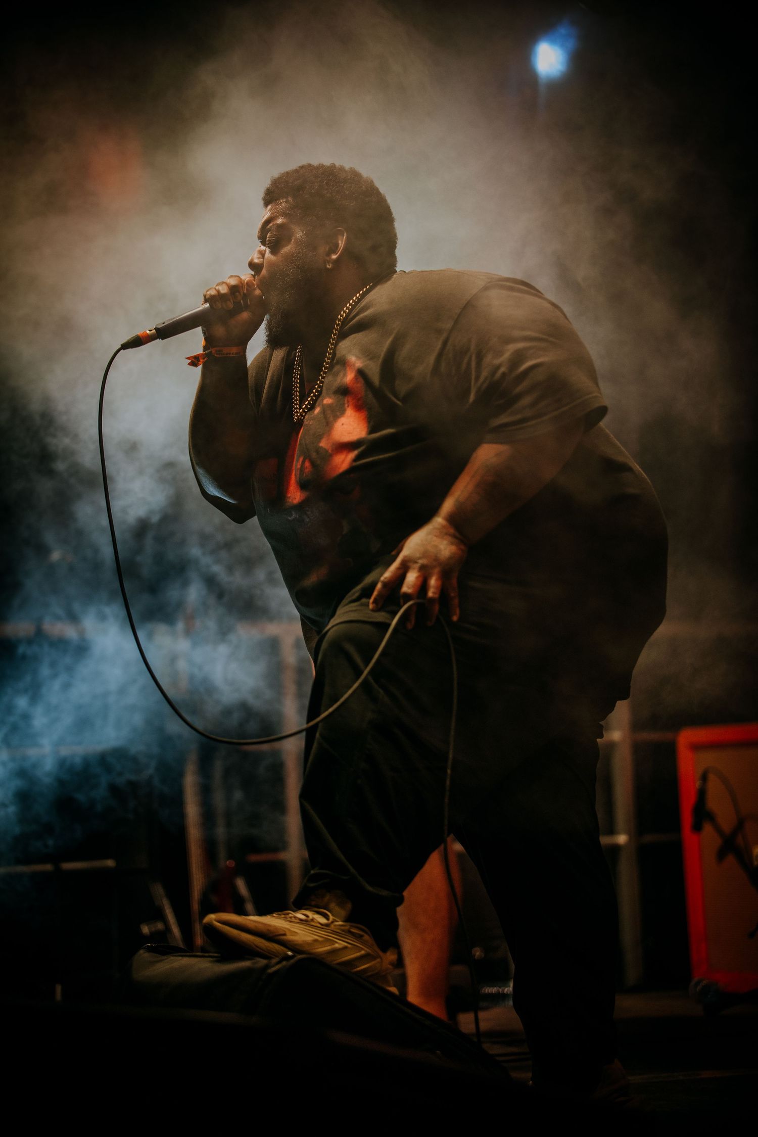 Performer silhouetted against smoky blue stage lighting in dramatic concert sequence.