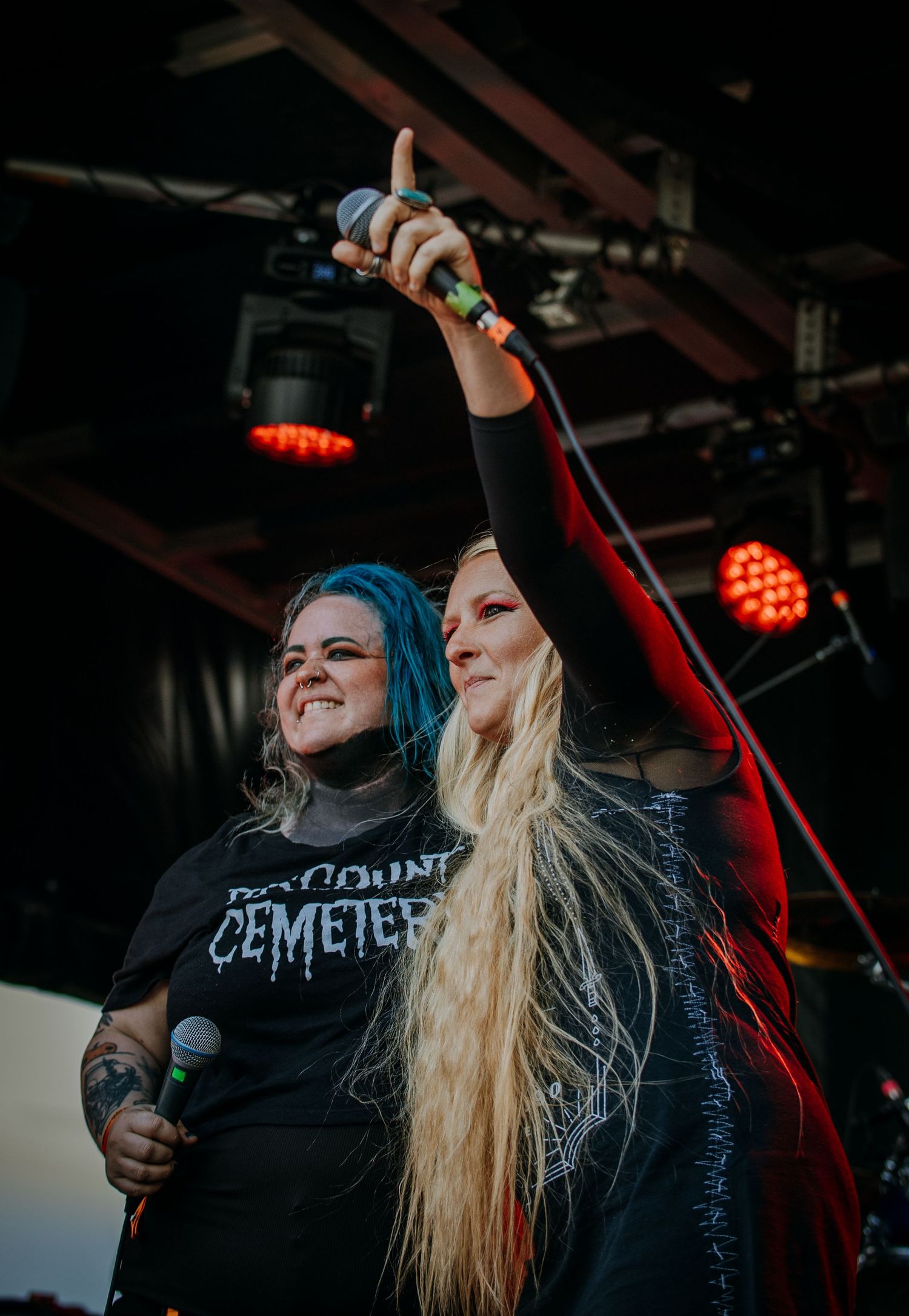 Female performers singing passionately on stage with dramatic red lighting effects.
