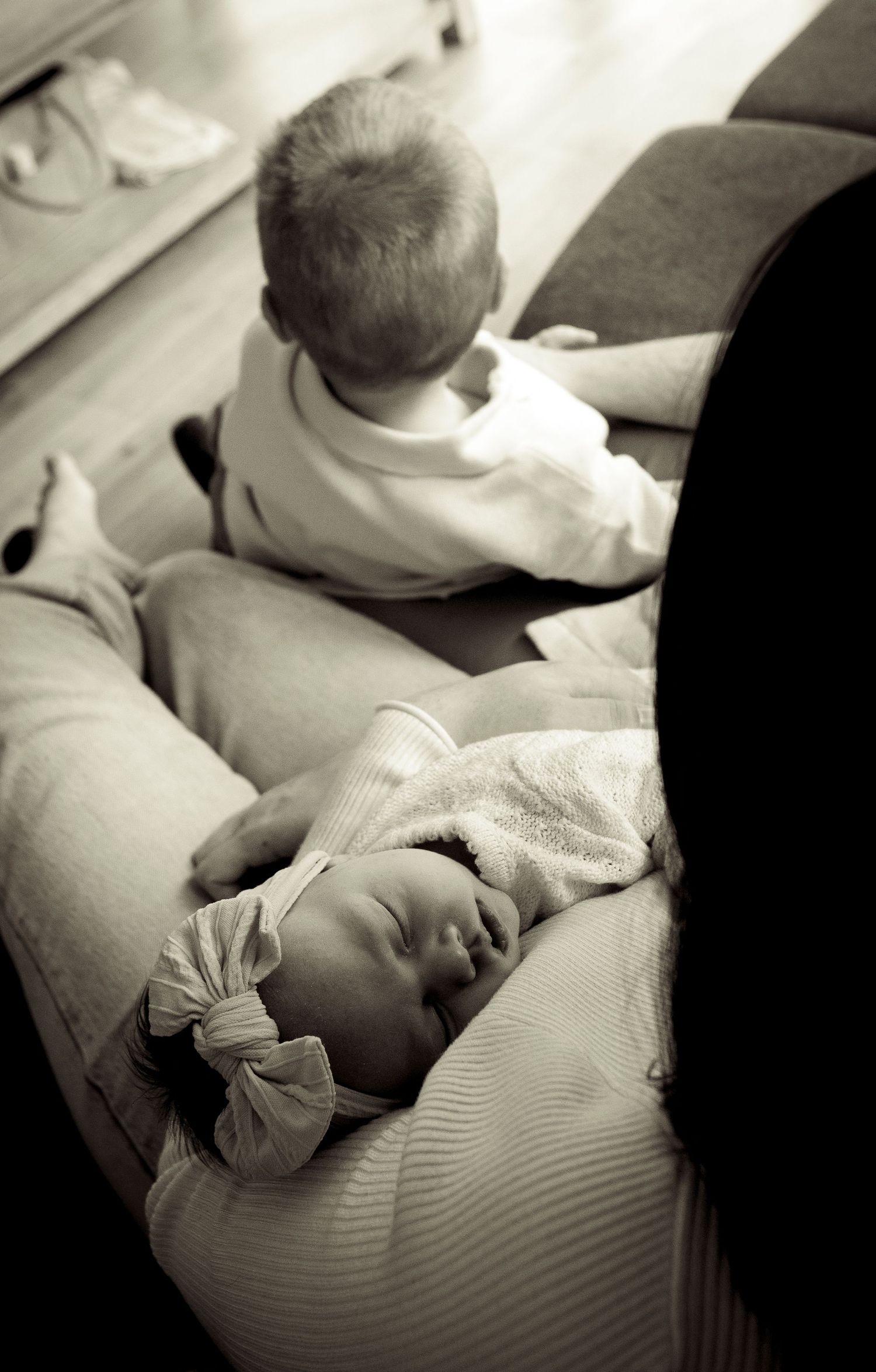 Black and white image of infants resting together on soft cushions.