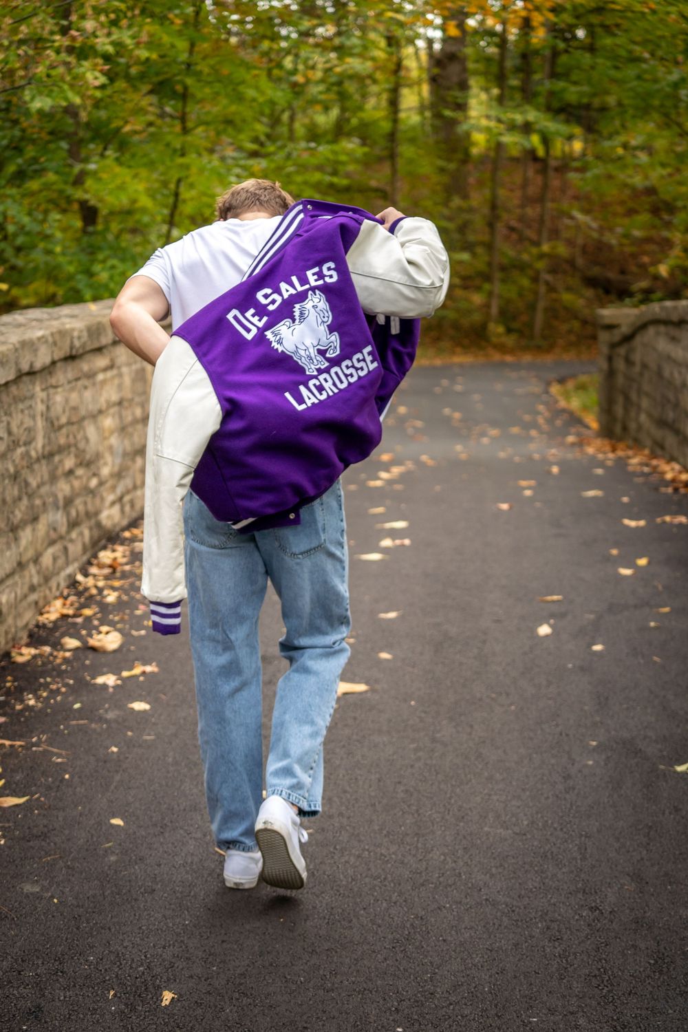 A series of sequential photos showing someone walking from behind on a paved path wearing purple varsity jacket and jeans.