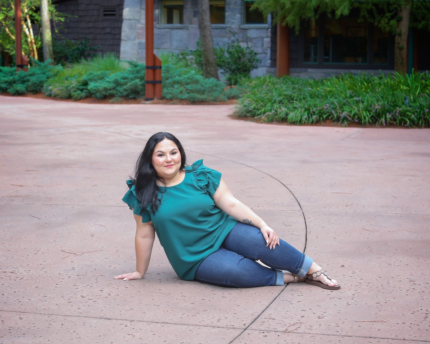 Person in teal shirt reclines on concrete ground in sequence of playful poses showing different angles.