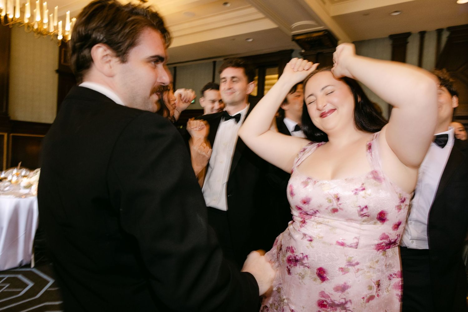 Festive wedding guests dancing and celebrating at a reception party in formal attire.