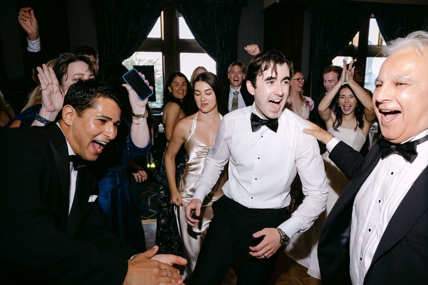 Wedding guests dance and celebrate energetically on the dance floor.