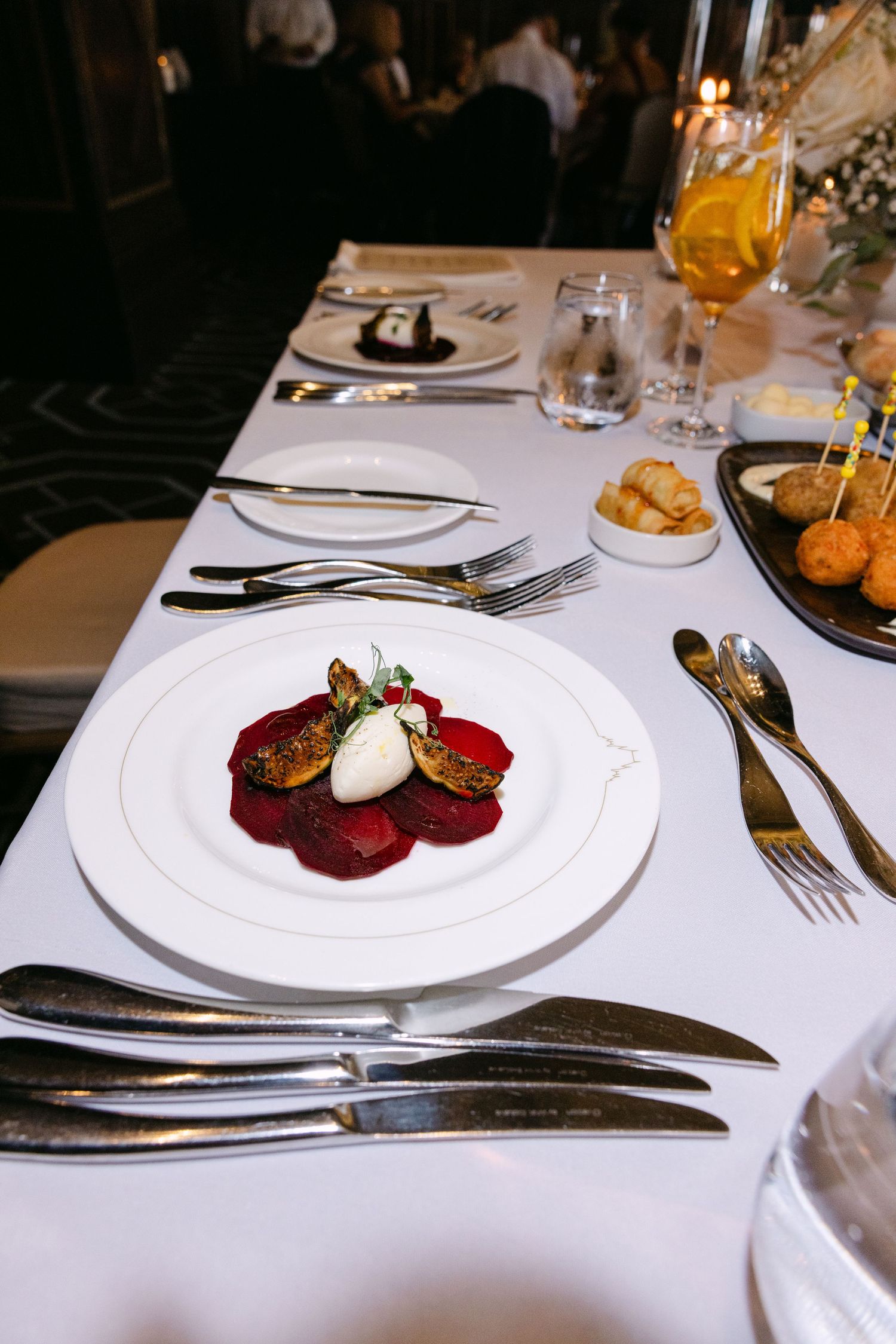 Elegant plated dinner course featuring roasted beets with cream sauce on a white plate at a formal event.