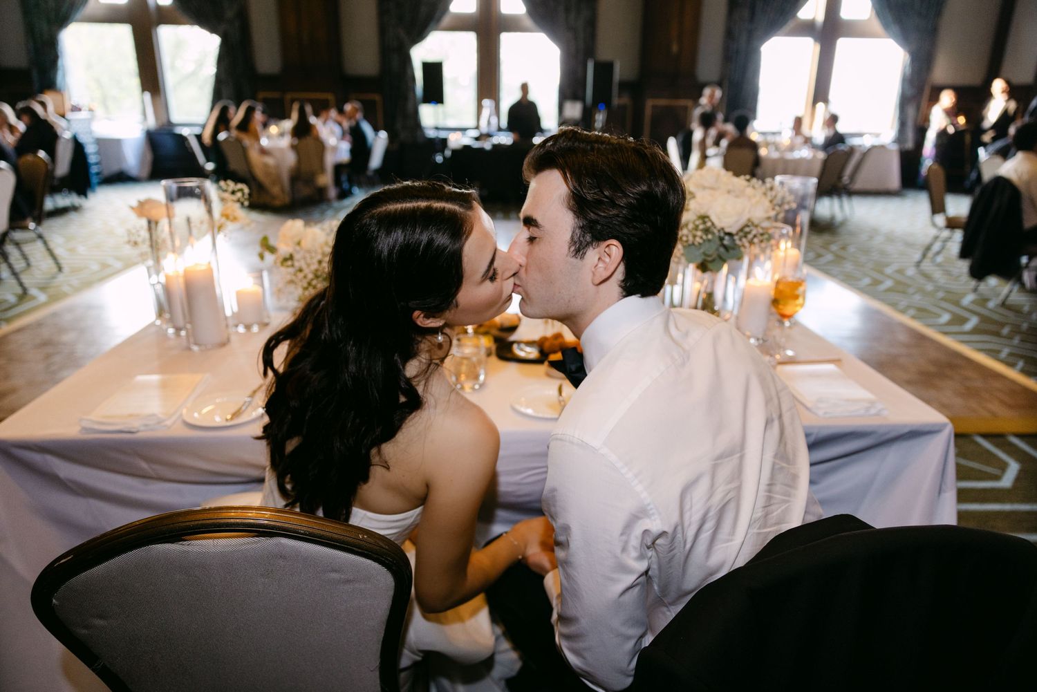 Intimate moment shared between couple at wedding reception table with candlelight.