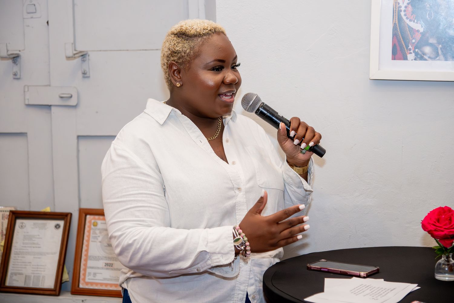 A person in a white jacket speaking into a microphone at what appears to be a professional event or presentation.