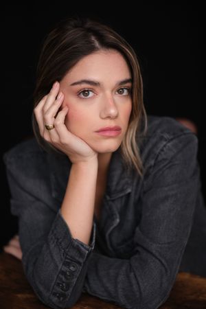 Moody portrait series with subject resting head on hand against dark background.