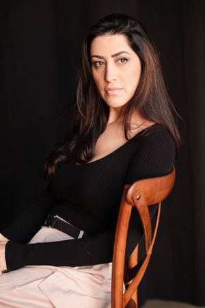 Casual portrait series in a black sweater while seated on a wooden chair.