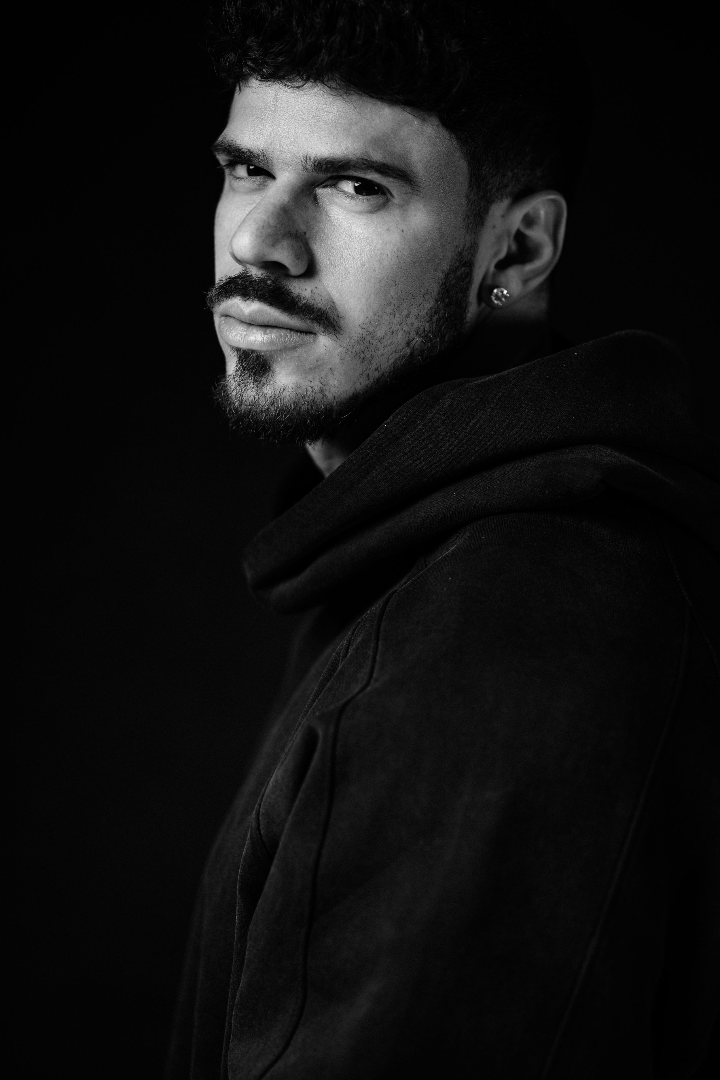 Moody black and white portrait sequence of person in hoodie with dramatic side lighting.