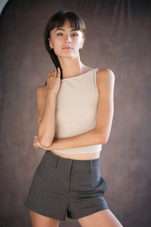 Fashion portrait of model in beige sleeveless top and grey shorts.