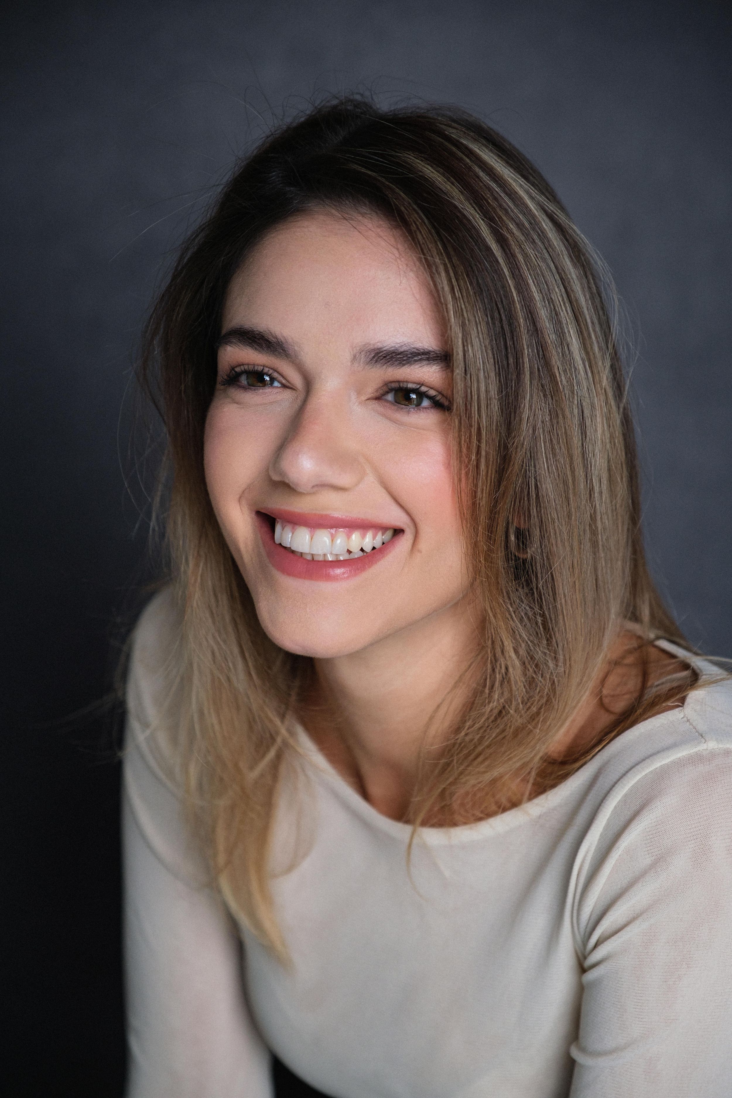 Studio portrait series with cream sweater showing natural expressions against dark background.