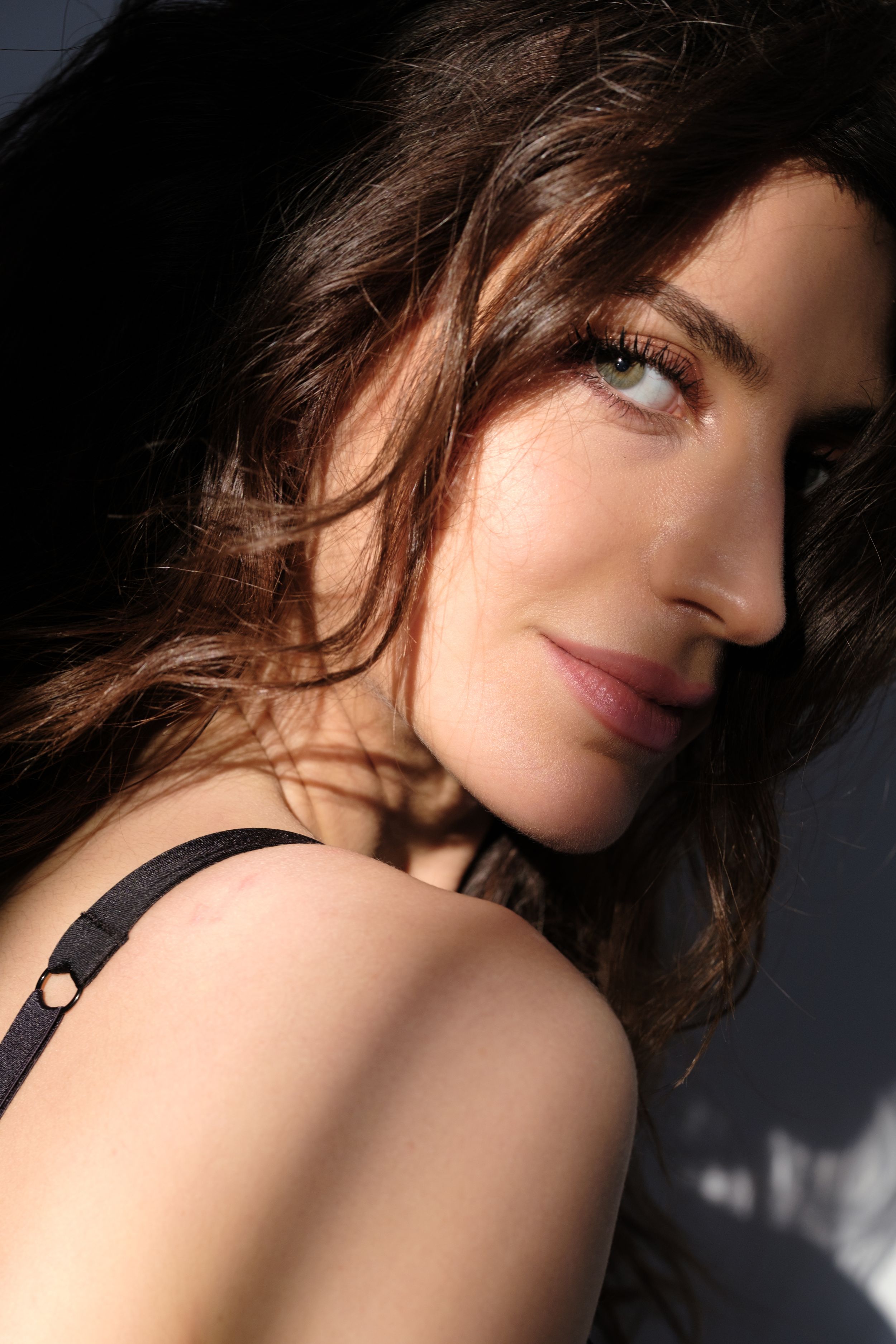Artistic close-up portrait with dramatic lighting highlighting soft skin tones and shadows.