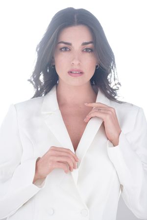 High-key portrait of model in white blazer against bright background.