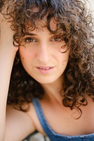 Close-up portrait of a woman with natural curly hair wearing a blue top.
