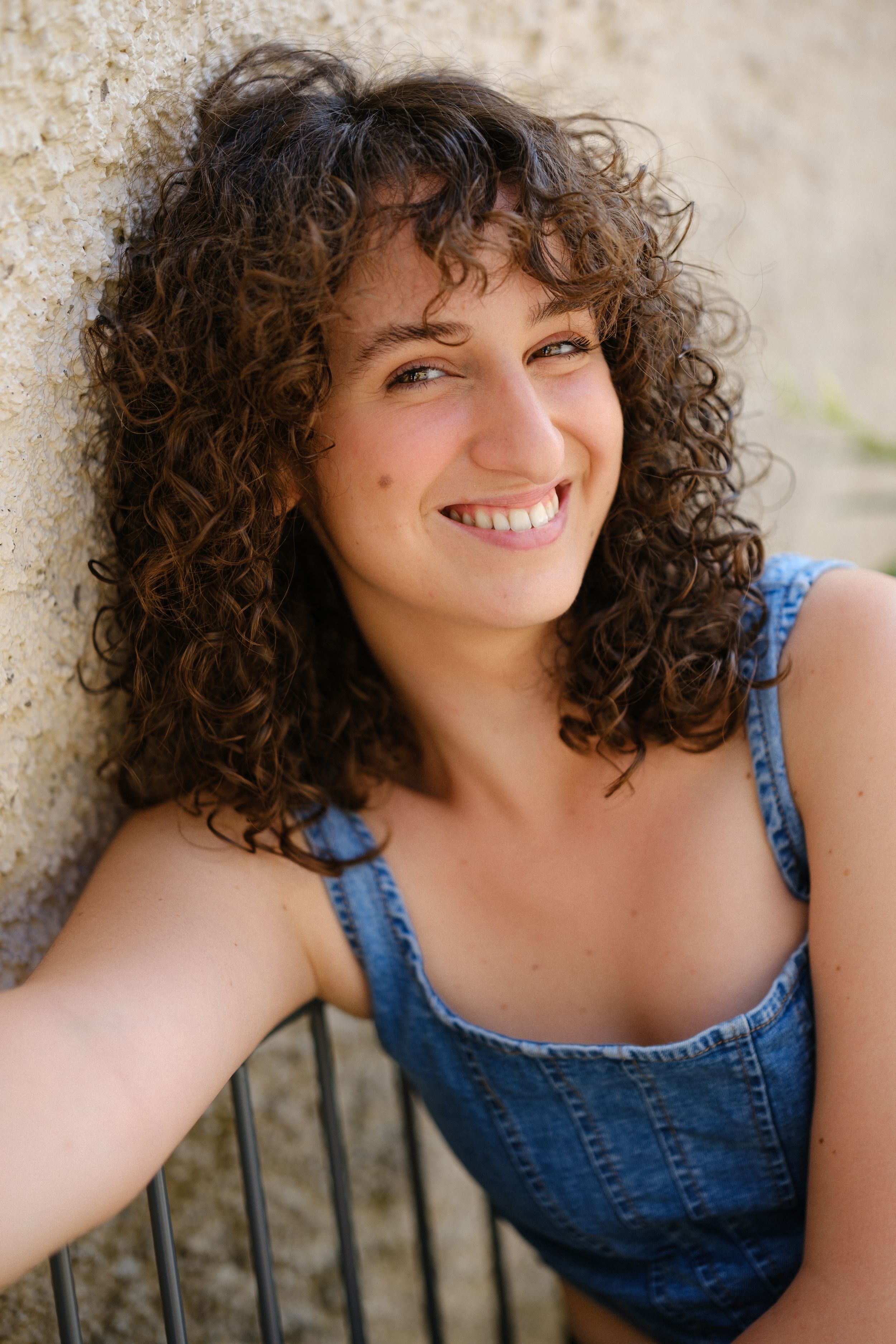 Outdoor portrait series in denim showing natural curly hair and casual poses.