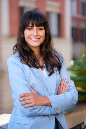 Professional outdoor portraits in a light blue blazer against brick building backdrop.