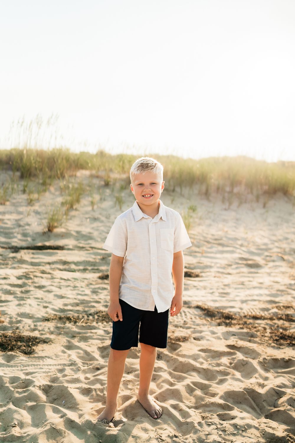 Five sequential beachside photos showcase someone in a white shirt and black shorts standing in golden sunlit sand.