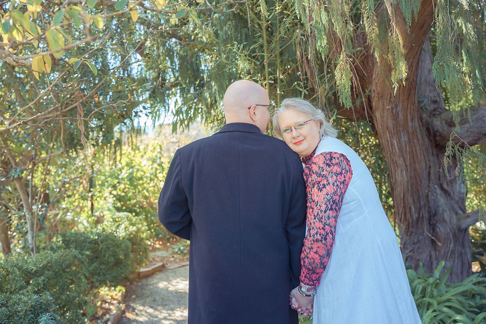 A couple shares an intimate moment together on a garden path surrounded by eucalyptus trees.