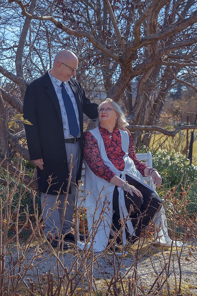 People enjoy an autumn day while exploring a garden path with bare trees and branches in the background.