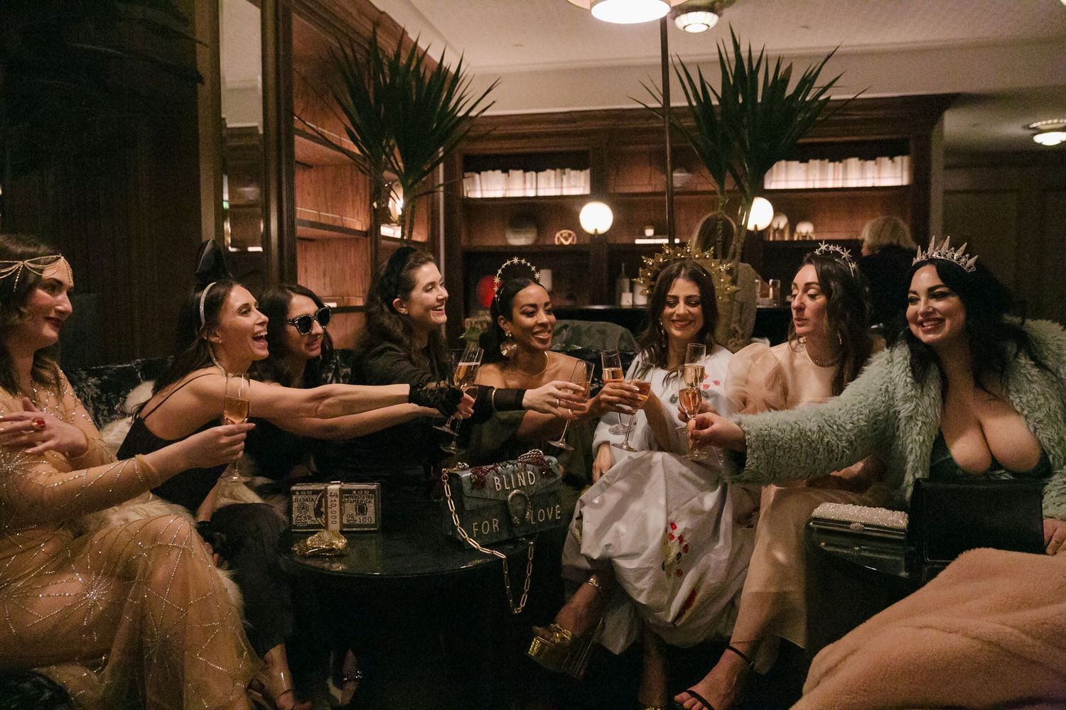 Friends raise glasses in celebration at a dimly lit restaurant gathering.