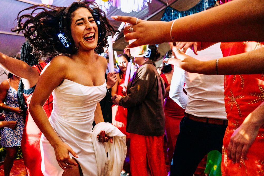 Joyful bride in white strapless dress dancing energetically at wedding reception party.