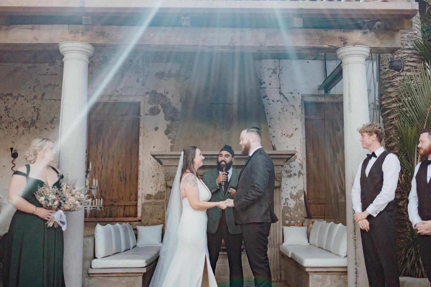 A wedding ceremony with sunbeams streaming through from above, captured by Apertured Media Auckland Wedding Photographer.