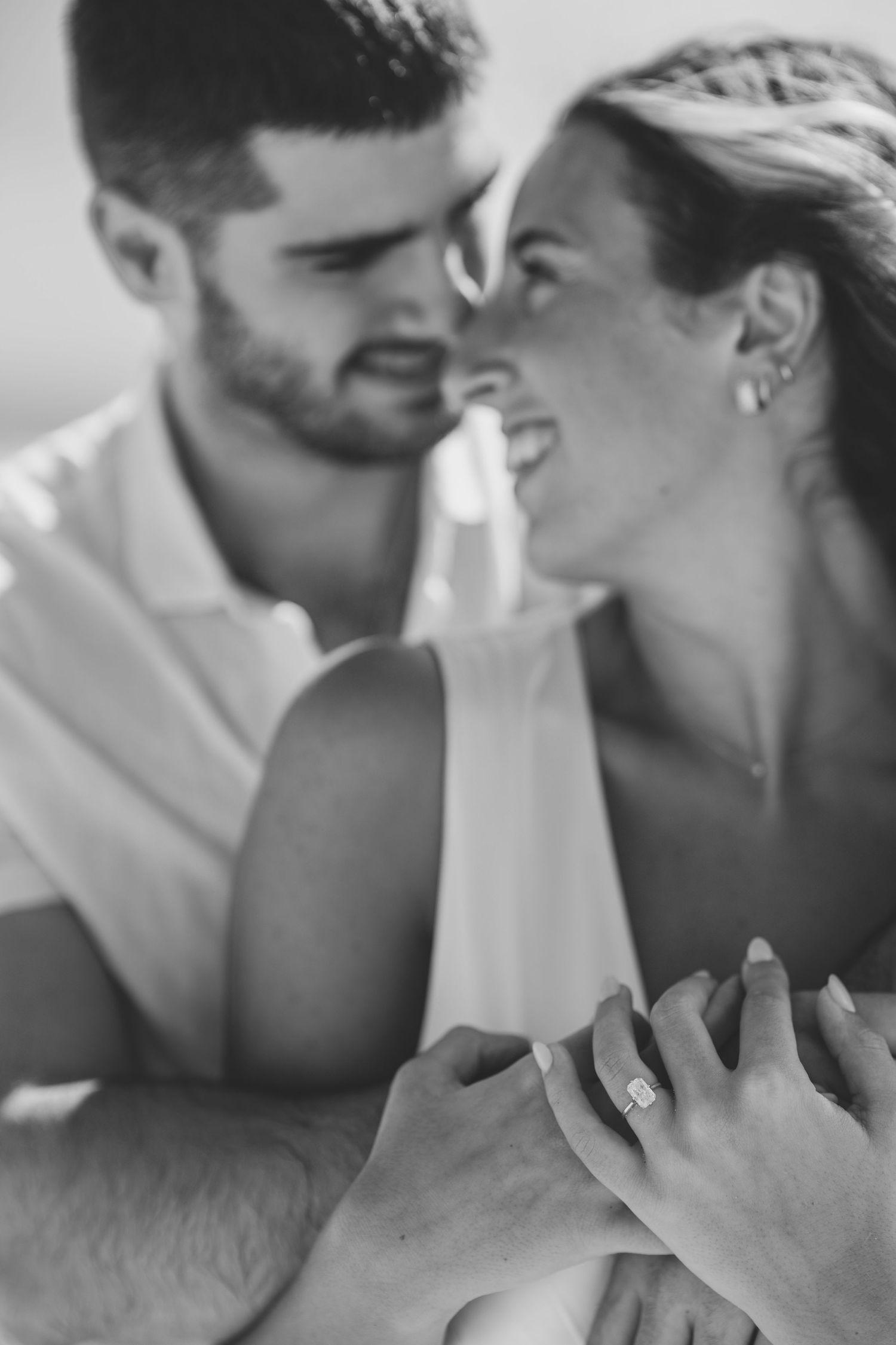 A romantic black and white close-up of a happy couple sharing an intimate moment together, holding hands.