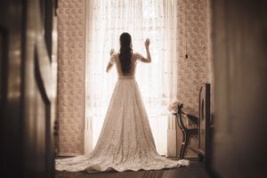 Fotografisanje venčanja 
Mlada obučena u venčanici pomera zavesu na prozoru dok čeka mladoženju. 
Apatin
Vojvodina
