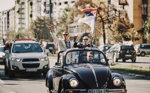 Fotografisanje venčanja na ulicama grada Novog Sada u mladenačkom autu bez krova voze se mladoženja i kum.