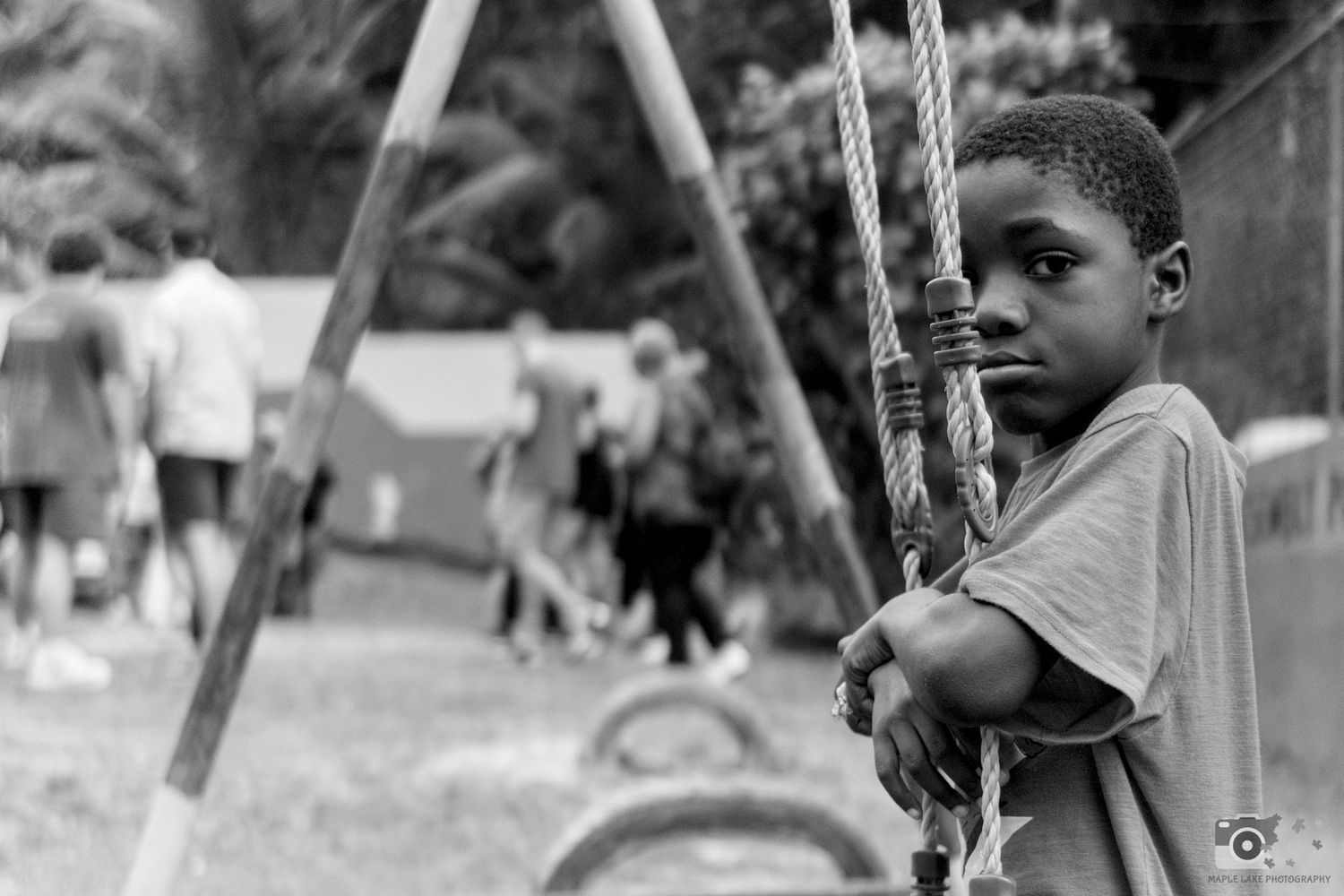 A child holding swing chains in black and white on a playground.
