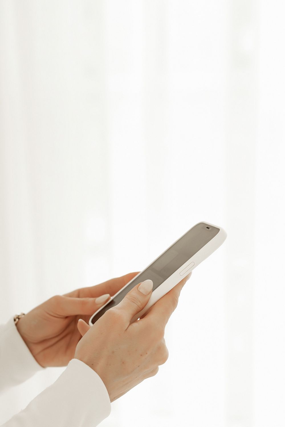 Hands holding and using a modern smartphone device against a white background.