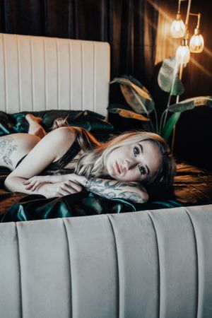 Dramatic close-up portrait on tufted grey couch with soft lighting and plant decor.