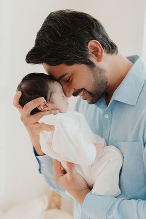 Three tender moments showing a couple with a newborn baby in soft white and pale blue tones.