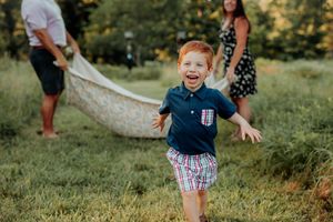 A child playing and smiling joyfully outdoors on a sunny summer day in a grassy field.
