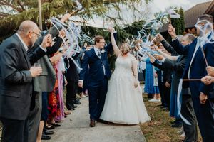 Wedding guests form a sparkler tunnel exit for newlyweds walking through at outdoor evening celebration.