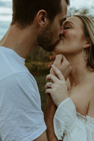 Romantic close-up sequence of a couple sharing an intimate kiss outdoors at sunset in white clothing.