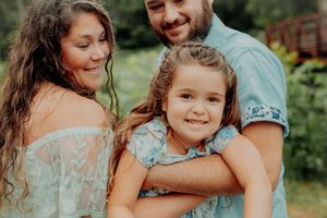 A happy family sharing an affectionate moment together outdoors with lush greenery in the background.