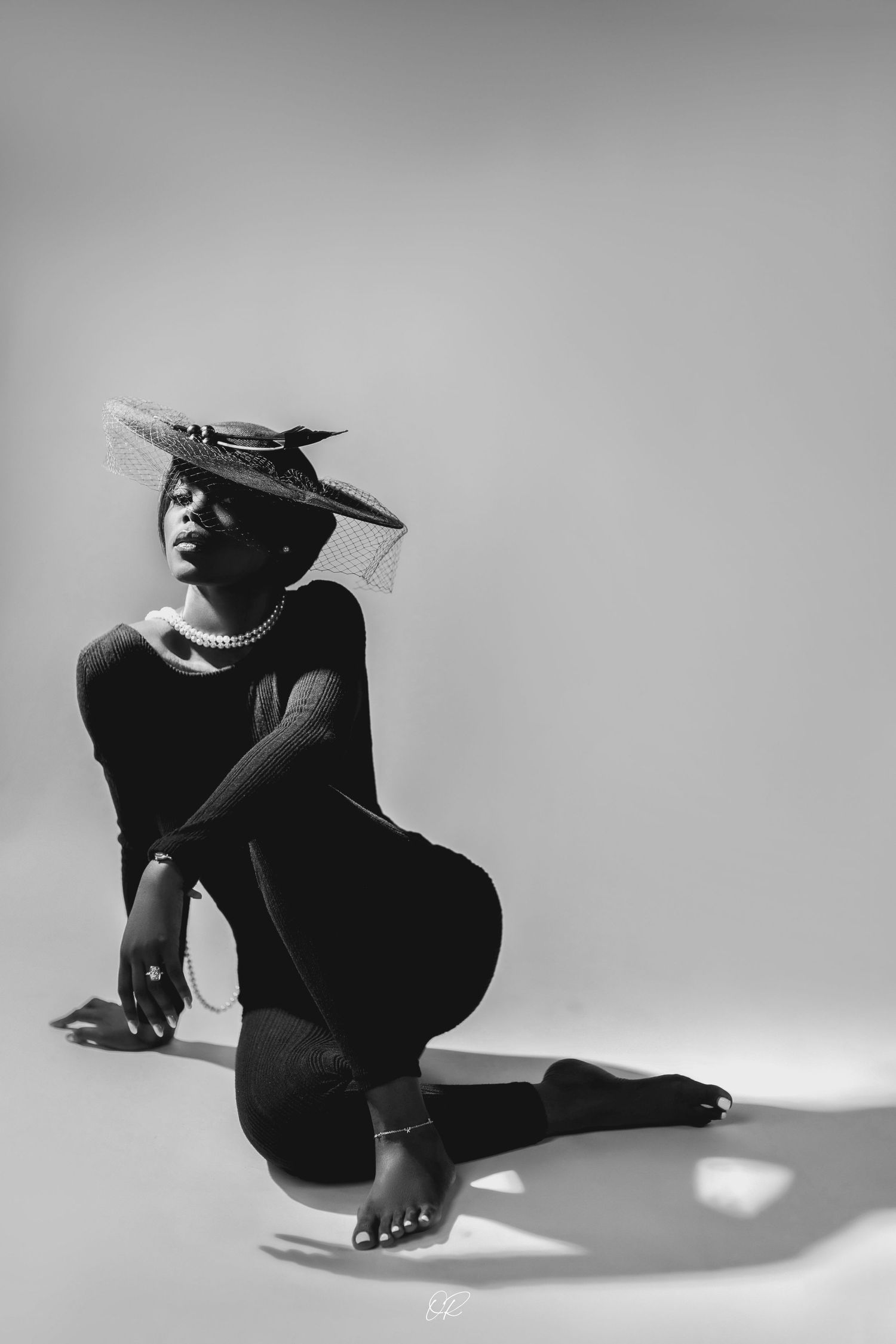Artistic black and white portrait of a dancer in dramatic pose with hat.