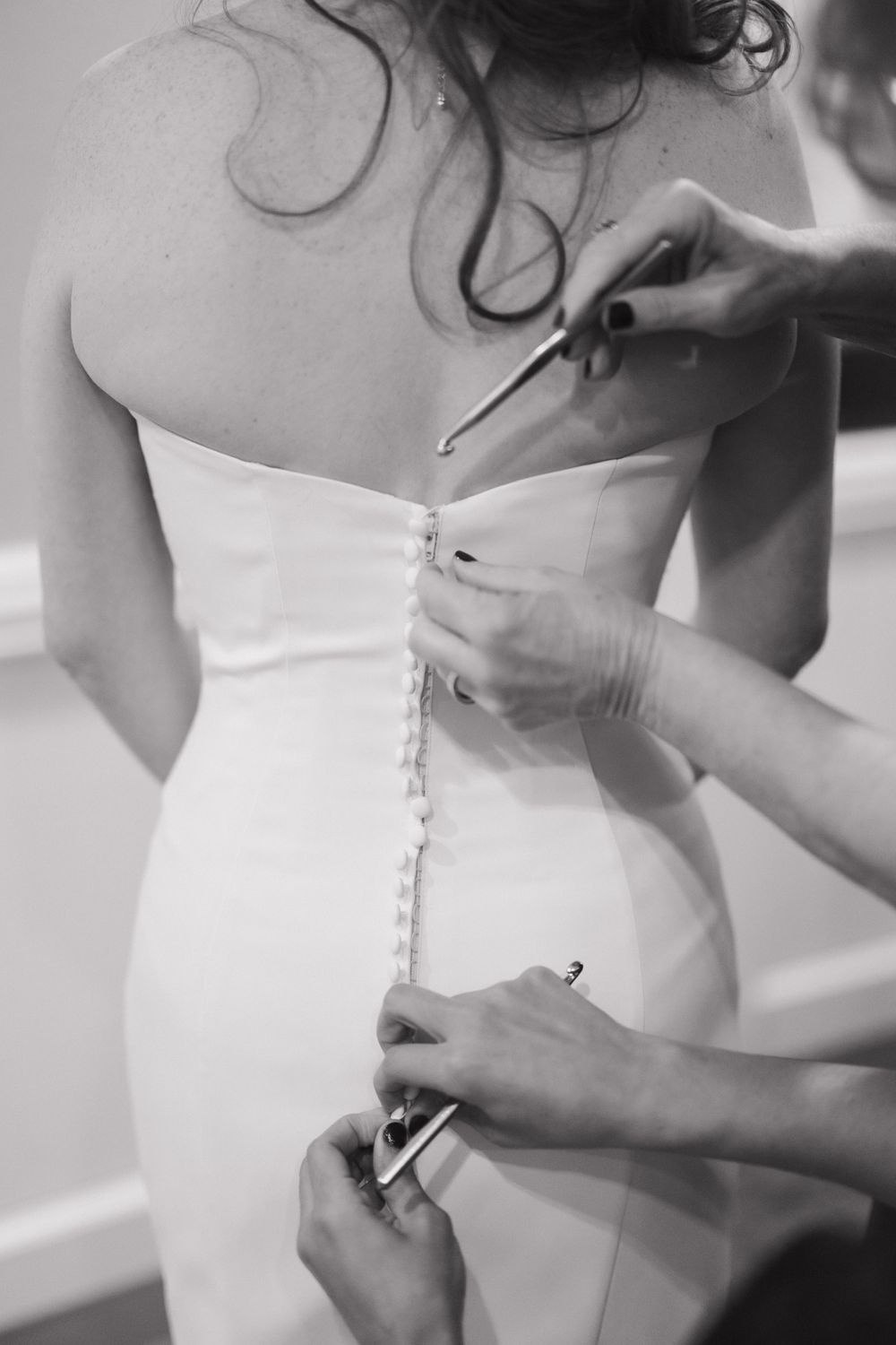 Close-up shots of hands lacing up a white wedding dress corset back.