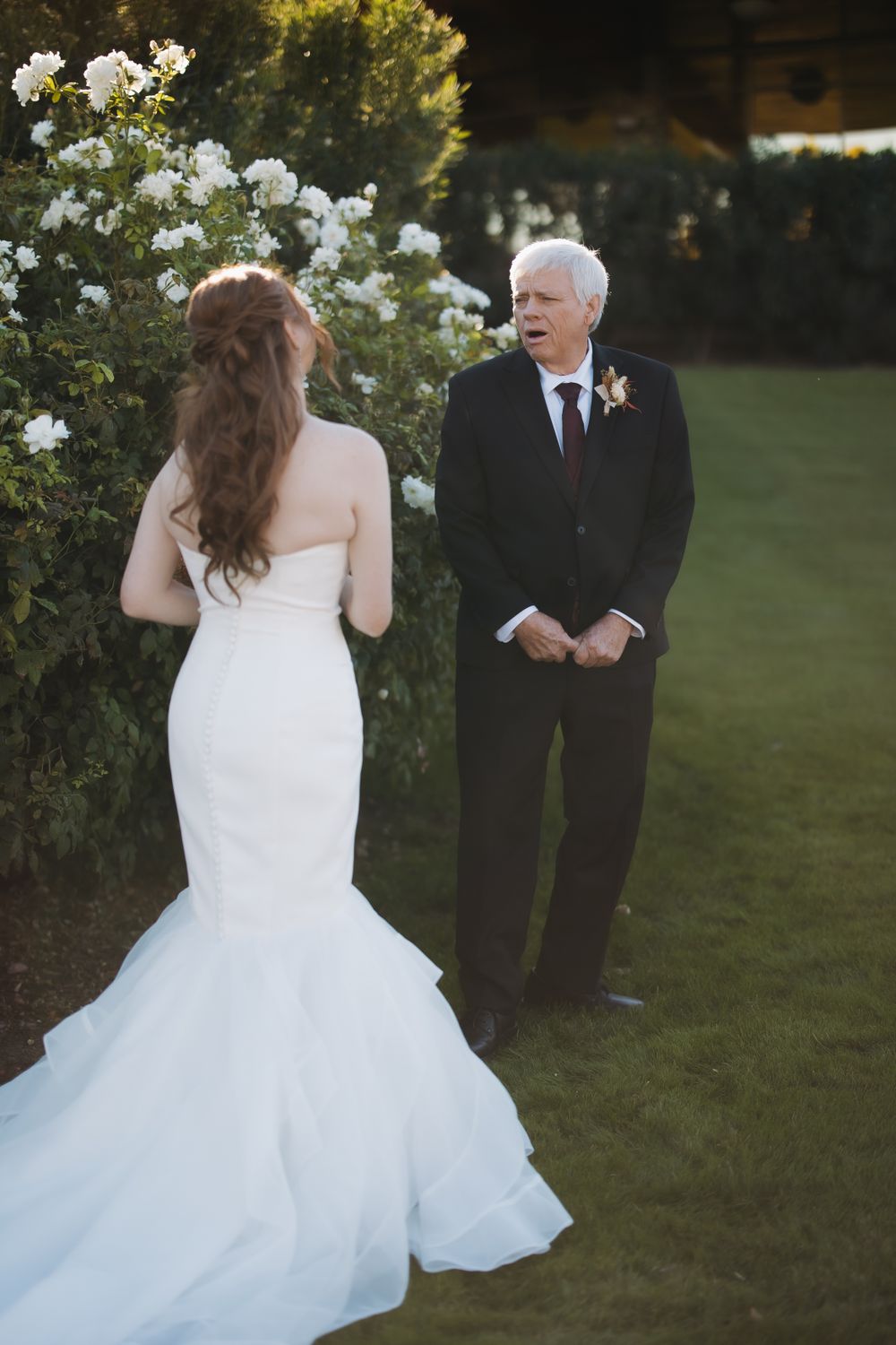A flowing white wedding dress twirls against a backdrop of blooming white roses.