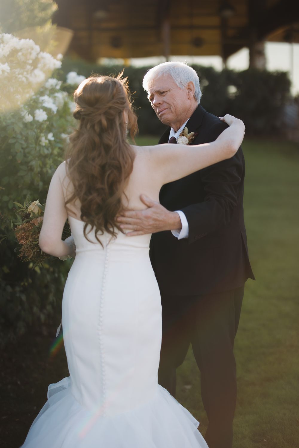 A white wedding dress spins gracefully in an outdoor garden setting at sunset.