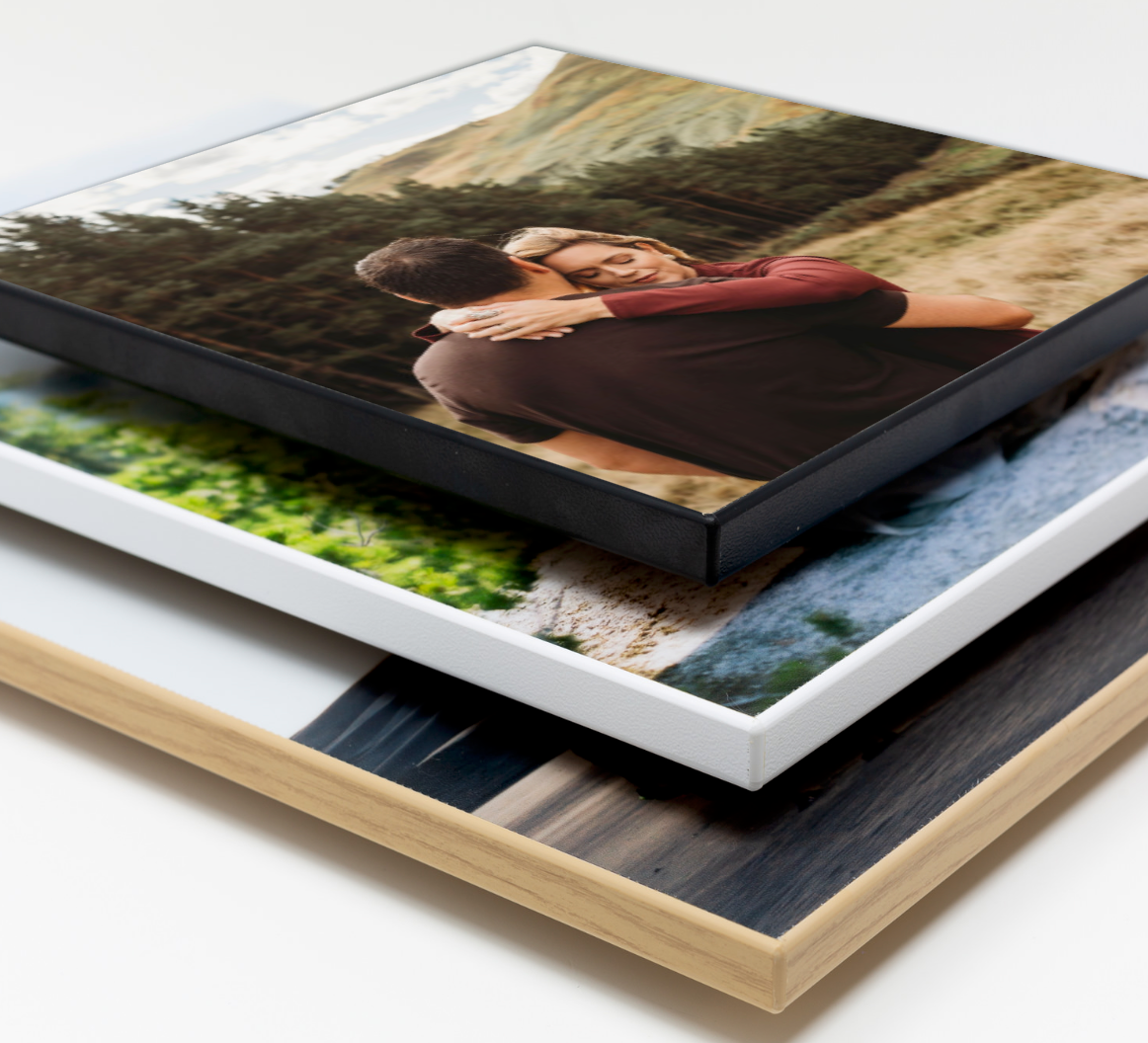 Stack of mounted photo prints showing layered gallery wrap canvas and traditional photo prints with different finishes.