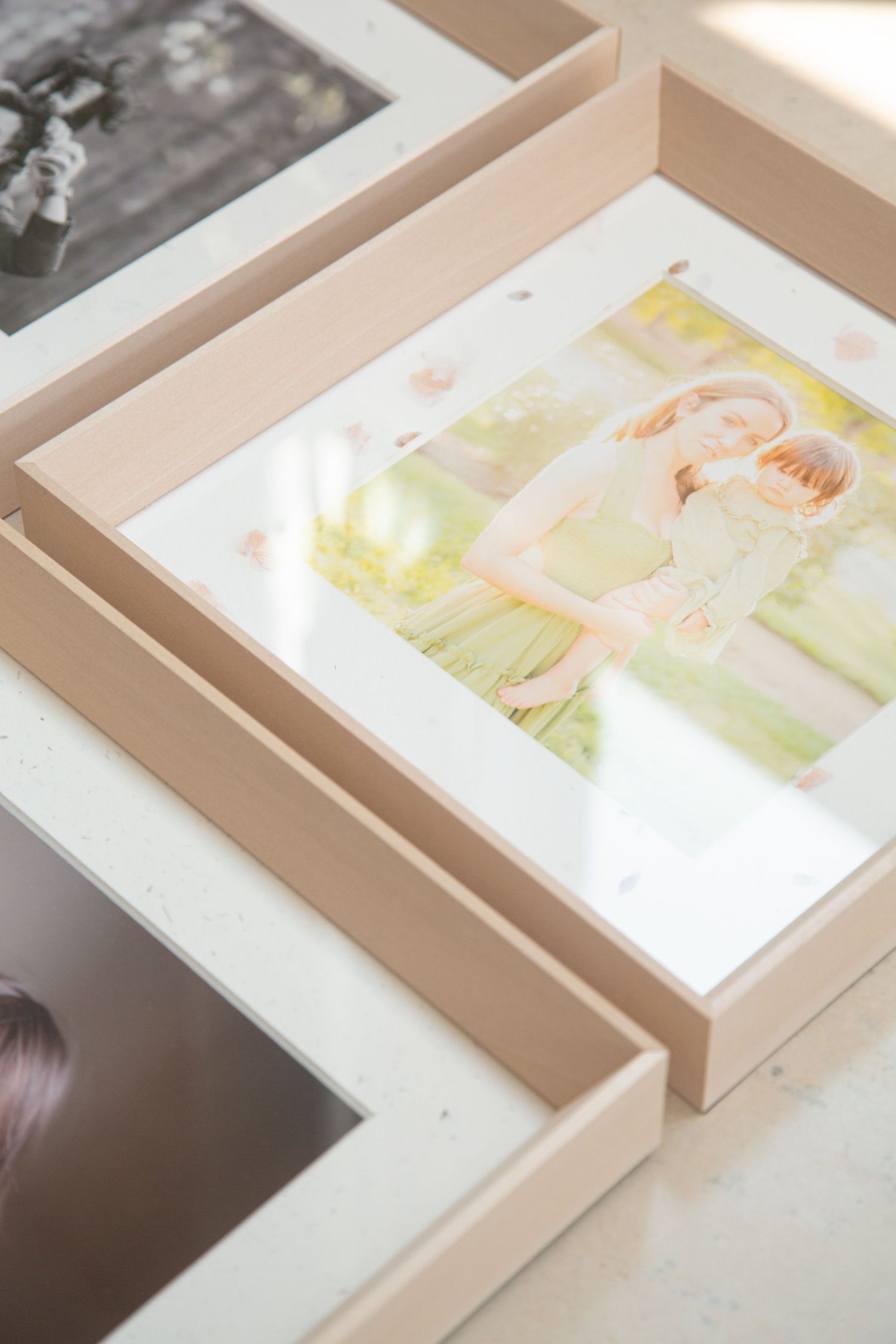 An elegant white keepsake photo box with a fabric ribbon handle sits in soft natural lighting.