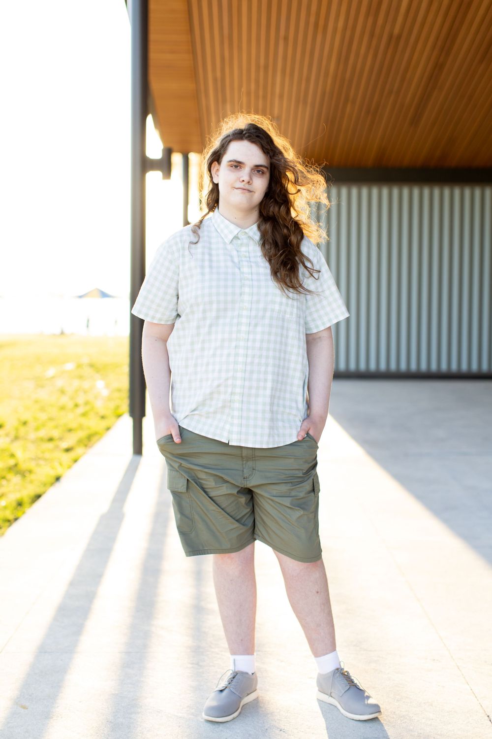 Casual summer outfit with checkered shirt, khaki shorts, grey sneakers and white socks on a sunny porch. Twin cities senior photography.