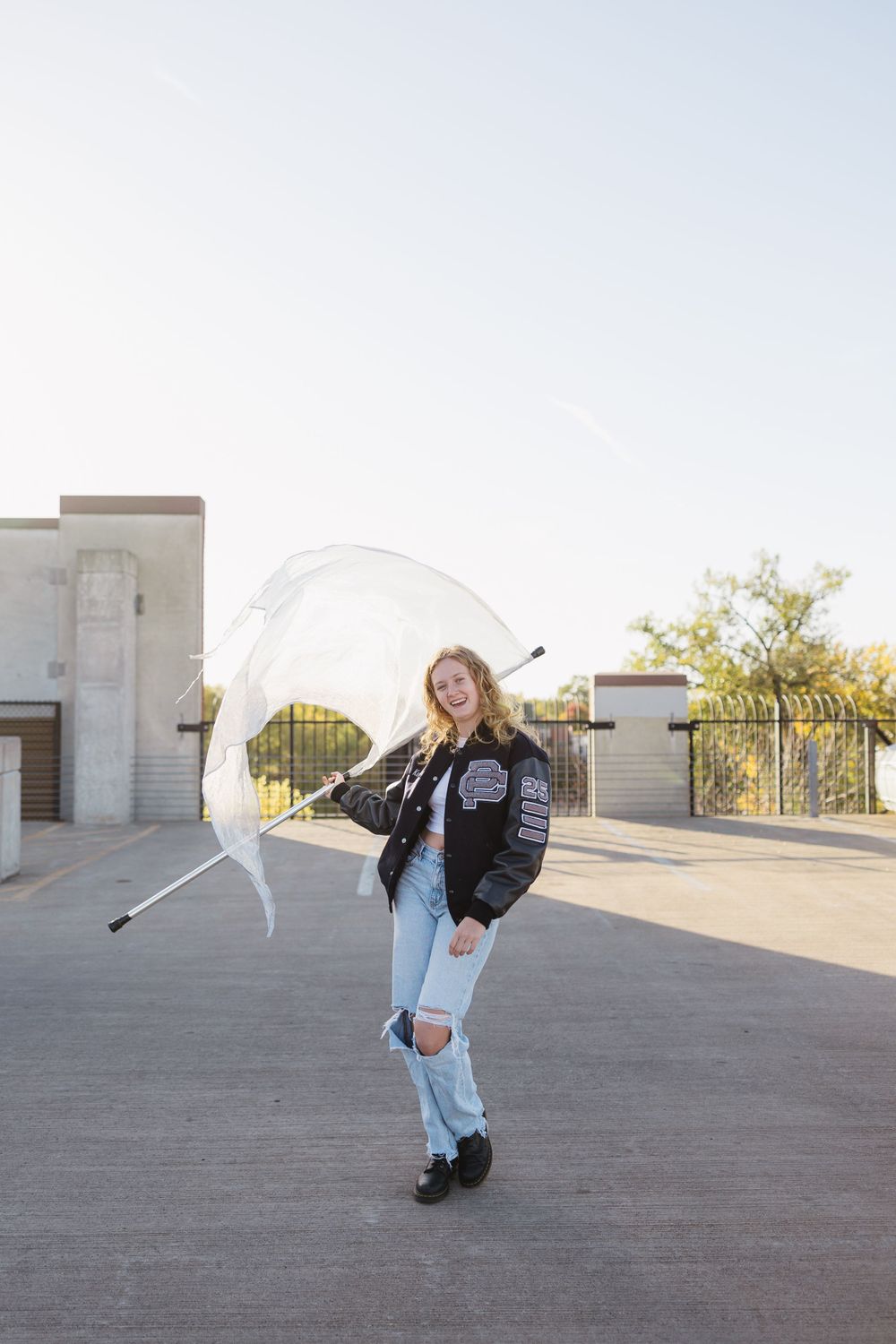 Casual student with leather jacket twirling in an urban setting against a bright sky.  Twin Cities senior photography.