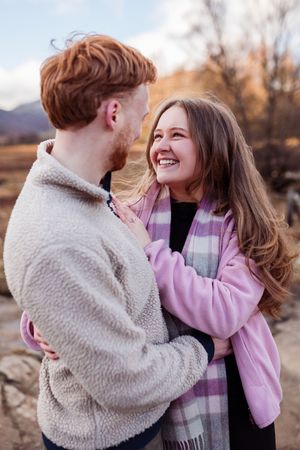 A couple shares intimate moments outdoors during golden hour while wearing cozy winter attire.