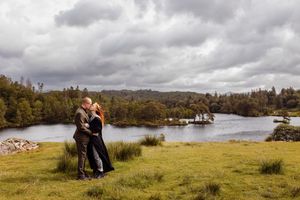 A lakeside engagement photography session with cloudy skies and natural scenery creates a romantic atmosphere.