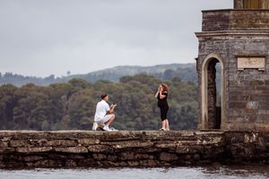 A scenic panorama shows several people enjoying views from an ancient stone wall overlooking misty mountains.