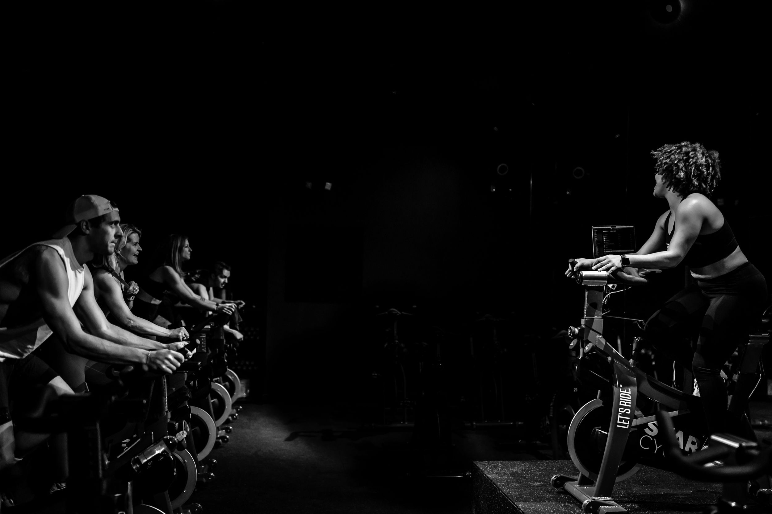 Black and white image of a spin instructor and students in Denver studio