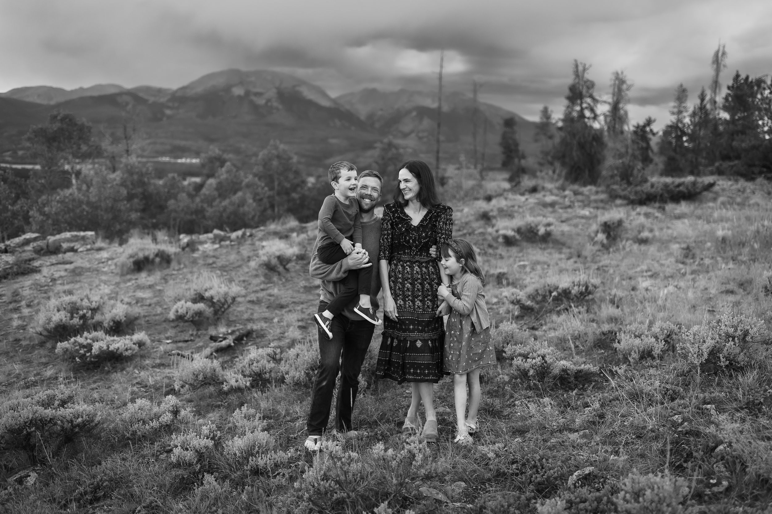 A black and white portrait of a Colorado family in Dillon with dramatic mountains and clouds behind them